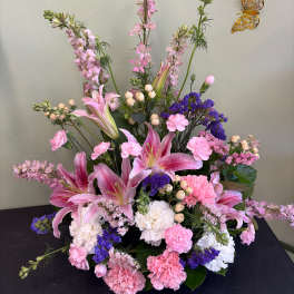 Pink lilies and carnations arranged with purple filler flowers