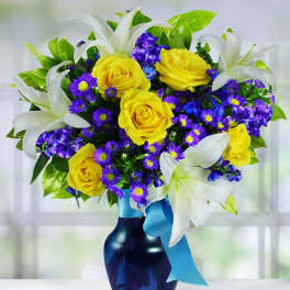 Bouquet of yellow roses, purple flowers, and white lilies in a blue vase