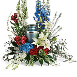 Floral arrangement around a blue urn with red, white, and blue flowers