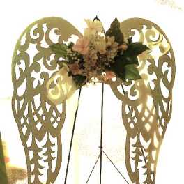 Floral arrangement on decorative angel wings with pale flowers and dark green leaves