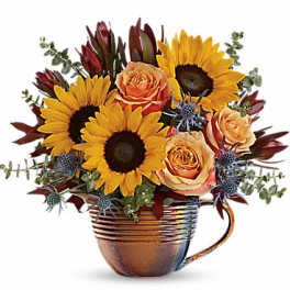Sunflowers and peach roses arranged in a copper mug