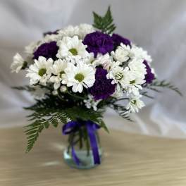 Bouquet of white daisies and purple carnations in a glass vase