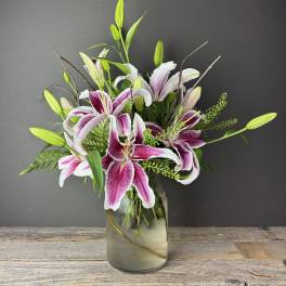 Pink and white lilies arranged in a glass vase