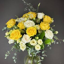 Yellow and white roses arranged in a clear glass vase