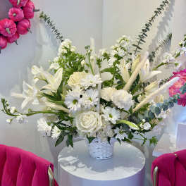 White floral arrangement in a white basket with pink wall accents