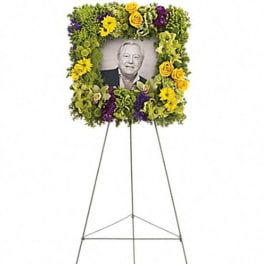 Standing floral tribute on an easel with a framed portrait in the center