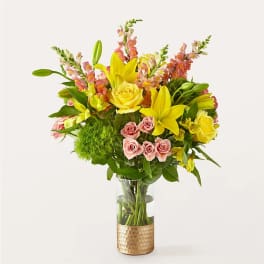 Bouquet of yellow lilies, pink roses, and snapdragons in a glass vase
