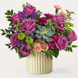 Purple roses and mixed flowers arranged in a striped vase with a succulent center