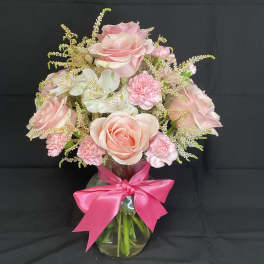 Pink roses and carnations in a glass vase with a bright pink bow