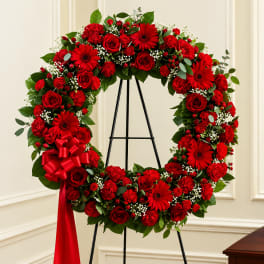 Red floral wreath on a black stand with a red ribbon bow