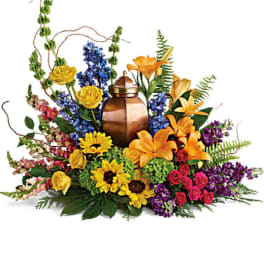 Colorful floral arrangement around a copper urn with lilies and roses