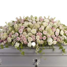 Pastel pink and white floral casket spray on a silver casket