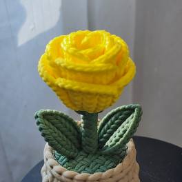 Yellow rose in a woven basket-style container with green leaves