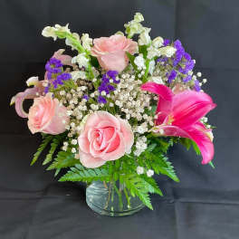 Pink roses and a bright pink lily in a glass vase