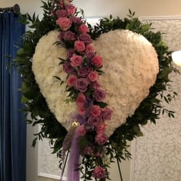 Heart-shaped floral tribute with pink and purple roses on an easel