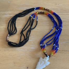 Two beaded necklaces with a white pendant on a wooden surface