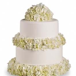 Three-tier white cake with ivory floral garlands and topper