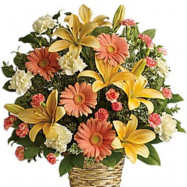 Basket arrangement with yellow lilies, peach daisies, and small pink and white blooms