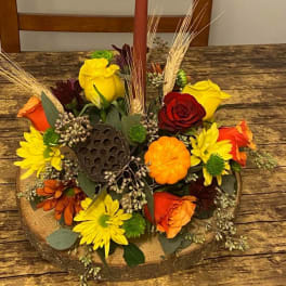 Autumn floral centerpiece with a tall candle in a wooden base