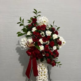 Standing floral spray with red roses and white daisies on a black easel