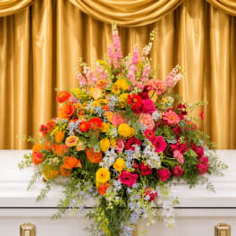 Colorful floral casket spray with roses, daisies, and snapdragons