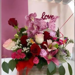 Pink and red flower arrangement with a love sign and butterfly decoration