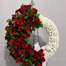 Heart-shaped floral wreath with red and white flowers on a stand