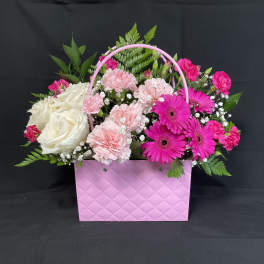 Pink and white flowers arranged in a pink handled gift box