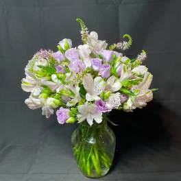 Lavender and white flowers arranged in a clear glass vase