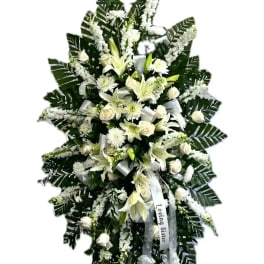 White funeral standing spray with lilies and roses on an easel