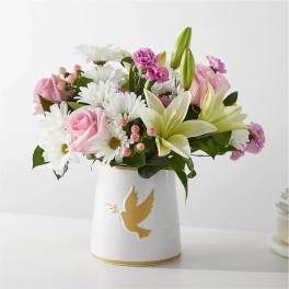 Pink and white mixed flower arrangement in a white vase with a gold dove