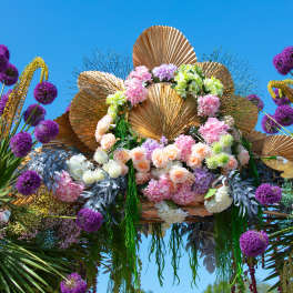 Large floral display with pink and white roses, purple allium-like blooms, and gold fan decorations