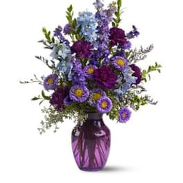 Purple and blue mixed flowers in a purple glass vase