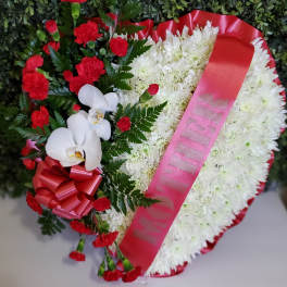 Heart-shaped floral wreath with white chrysanthemums, red carnations, and orchids