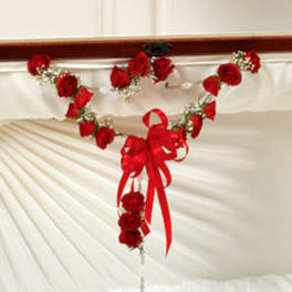 Red rose garland with a ribbon bow and hanging cross