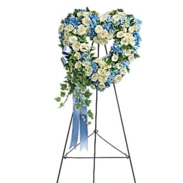 Heart-shaped floral standing wreath on an easel with blue and white flowers