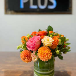 Orange and pink flowers arranged in a glass vase