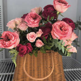 Pink and burgundy roses arranged in a wicker basket