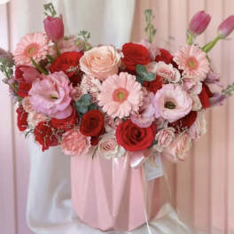 Pink and red bouquet with roses, gerbera daisies, and tulips in a pink wrap
