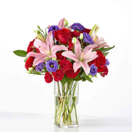 Bouquet of red roses and pink lilies in a clear glass vase