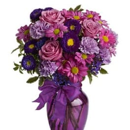 Purple and pink mixed bouquet in a purple vase with a ribbon