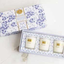 Three scented candles in a floral gift box with blue-and-white packaging