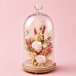 Pink roses under a glass dome on a wooden base