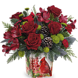 Red roses and red flowers in a holiday vase with pinecones