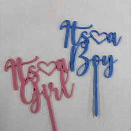 Pink and blue baby shower cake toppers reading "It's a Girl" and "It's a Boy"
