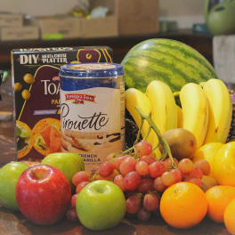 Assorted fruit and snack gift basket with bananas, apples, grapes, and packaged treats