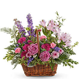 Mixed pink and purple flowers arranged in a wicker basket
