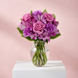Pink and purple bouquet of roses, carnations, and alstroemeria in a glass vase