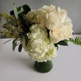 White roses and hydrangeas in a green vase