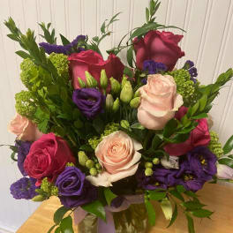 Mixed bouquet of roses and purple blooms in a glass vase
